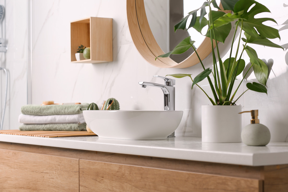 A white bathroom counter with a sink, plant, and towels in El Paso.